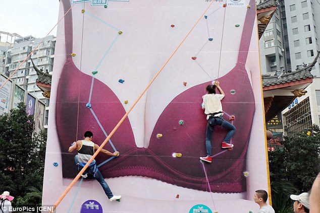 Rock climbers scale the 10-metre-high billboard, which appeared as part of a 'vulgar' beauty promotion in the middle of Changde City in China 